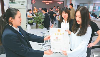 河北省承德市網(wǎng)絡(luò)代購經(jīng)營者陳晨(右)從工作人員手中接過帶有統(tǒng)一社會信用代碼的營業(yè)執(zhí)照。 劉環(huán)宇攝(人民圖片)