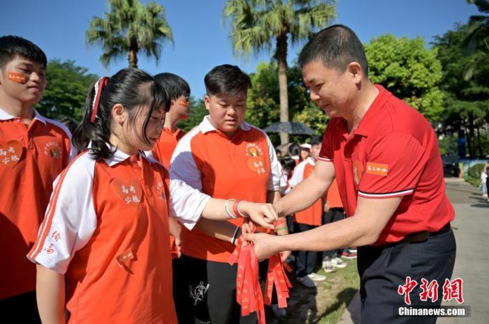 資料圖：廣西華僑實(shí)驗(yàn)高中的教師為高三學(xué)子系上紅絲帶，盼望學(xué)子高考必勝。 俞靖 攝