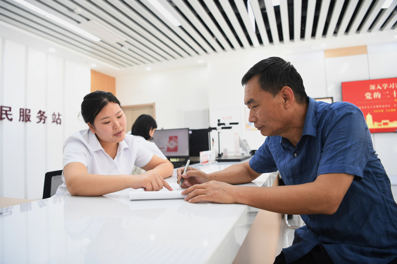 2023年5月23日，河北雄安新區(qū)容東片區(qū)南文營(yíng)社區(qū)居民（右）在社區(qū)便民服務(wù)站辦理業(yè)務(wù)。
